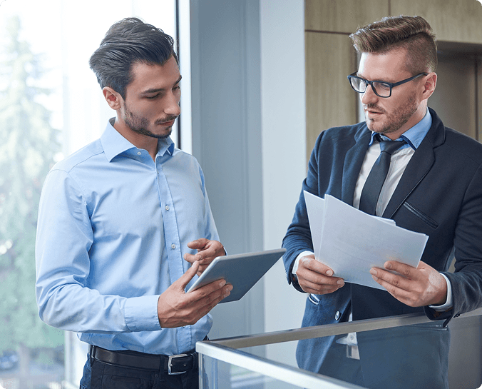 Two professionals reviewing documents in a meeting space.